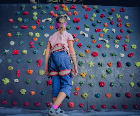 Foto de Un fuerte trepador sube una pared artificial con pintorescos agarres y cuerdas - Imagen libre de derechos