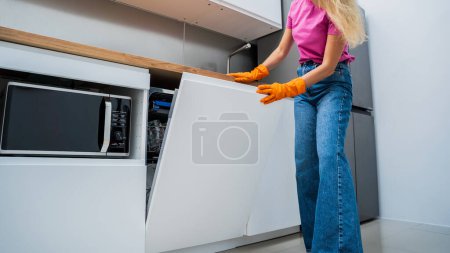 Foto de Mujer joven saca los platos de la máquina lavavajillas. - Imagen libre de derechos