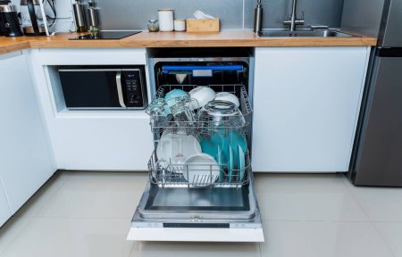 Téléchargez les photos : La cuisine blanche et lave-vaisselle ouvert avec vaisselle propre. - en image libre de droit