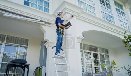 Photo for A technician sets up a CCTV camera on the facade of a residential building - Royalty Free Image