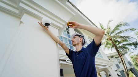 Foto de Un técnico instala una cámara CCTV en la fachada de un edificio residencial - Imagen libre de derechos