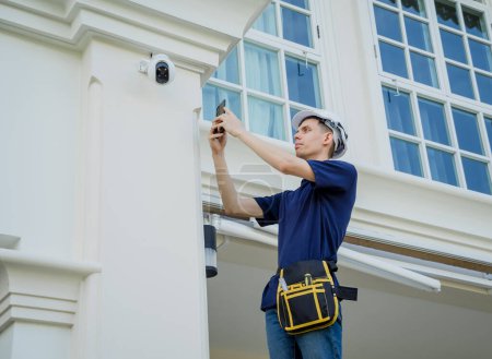 Photo for A technician sets up a CCTV camera on the facade of a residential building - Royalty Free Image