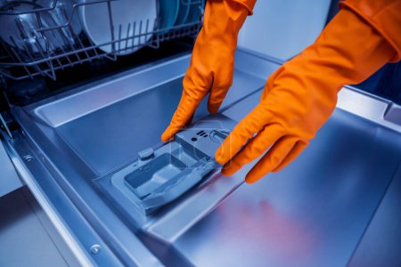 Photo for Woman adding detergent to dishwasher machine drawer. - Royalty Free Image