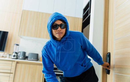 Téléchargez les photos : Un cambrioleur cambriolant un appartement pour voler quelque chose - en image libre de droit
