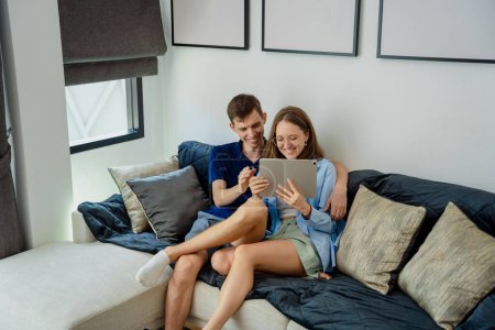 Téléchargez les photos : Jeune couple regardant les caméras de sécurité à domicile sur tablette. - en image libre de droit