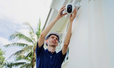 Foto de Un técnico instala una cámara CCTV en la fachada de un edificio residencial - Imagen libre de derechos
