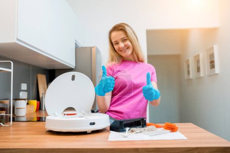 Photo for A young woman cleans a robot vacuum cleaner from dirt after cleaning - Royalty Free Image