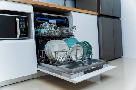 Foto de La cocina blanca y el lavavajillas abierto con platos limpios. - Imagen libre de derechos