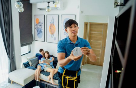 Téléchargez les photos : Technicien installant un détecteur de sécurité incendie dans un appartement moderne. - en image libre de droit