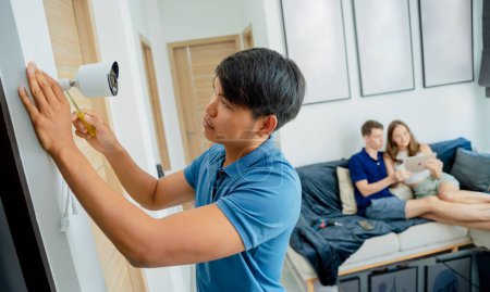 Téléchargez les photos : Un technicien installe une caméra de surveillance dans un appartement moderne - en image libre de droit