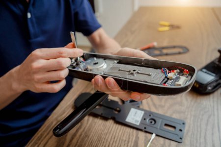 Téléchargez les photos : Un technicien assemble et installe une serrure électronique intelligente pour la protection de la maison. - en image libre de droit