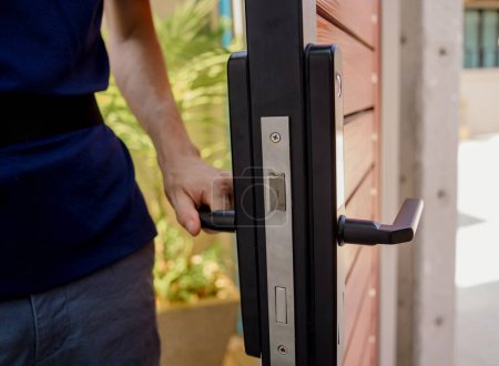 Téléchargez les photos : Un technicien installe une serrure intelligente moderne sur la porte en bois. - en image libre de droit