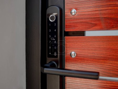 Téléchargez les photos : Serrure de porte intelligente moderne sur la porte en bois dans un appartement confortable. - en image libre de droit
