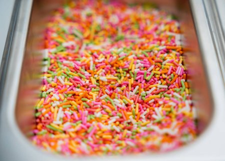 Foto de Espolvorear azúcar para hacer chocolates y caramelos hechos a mano en un taller. - Imagen libre de derechos