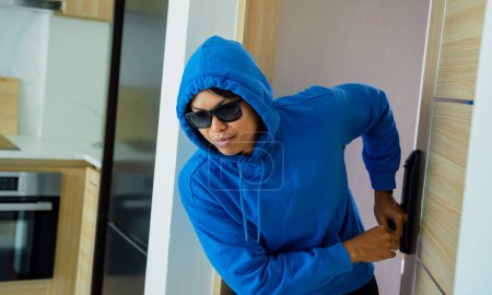 Photo for Burglar breaking in an apartment to steal something - Royalty Free Image