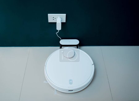 Photo for A robot vacuum cleaner at home moving towards the charging station - Royalty Free Image