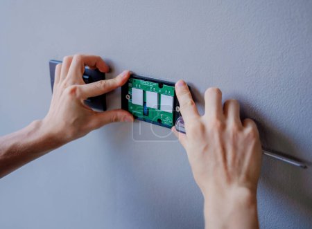 Foto de Técnico instalando interruptor de luz del sensor en villa moderna. - Imagen libre de derechos