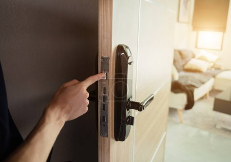 Foto de Un técnico instala una cerradura de puerta inteligente moderna en la puerta de madera. - Imagen libre de derechos