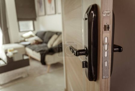 Téléchargez les photos : Serrure de porte intelligente moderne sur la porte en bois dans un appartement confortable. - en image libre de droit