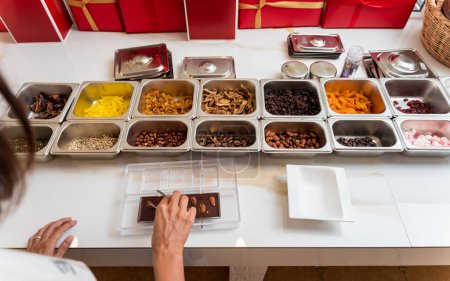 Foto de Mujer joven en el taller durante una lección sobre la fabricación de chocolates y dulces hechos a mano. - Imagen libre de derechos