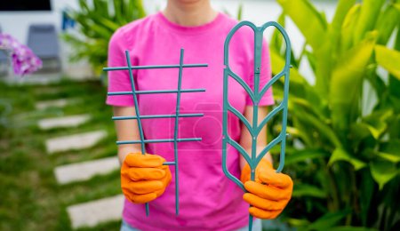 Téléchargez les photos : Une jeune femme s'occupe du jardin et attache les plantes. - en image libre de droit