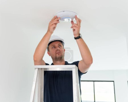 Téléchargez les photos : Technicien installe un projecteur LED dans le plafond - en image libre de droit