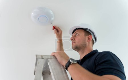 Photo for Technician is installing an LED spotlight in the ceiling - Royalty Free Image