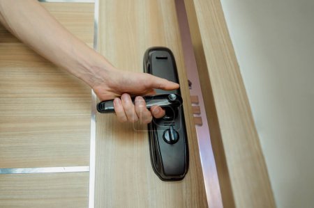 Téléchargez les photos : Un technicien installe une serrure intelligente moderne sur la porte en bois. - en image libre de droit