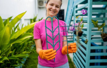 Foto de Una mujer joven cuida el jardín y ata las plantas. - Imagen libre de derechos