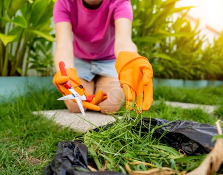 Una mujer joven cuida el jardín y corta la hierba.