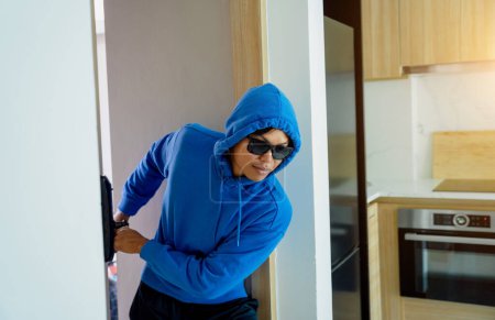 Photo for Burglar breaking in an apartment to steal something - Royalty Free Image