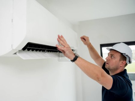 Téléchargez les photos : Technicien nettoie le système de climatisation dans un appartement moderne - en image libre de droit