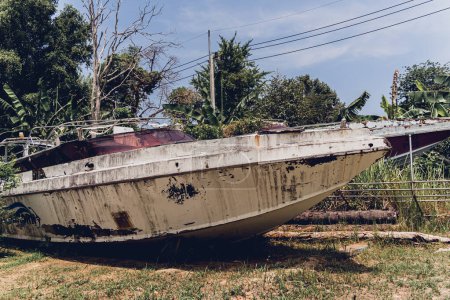 Téléchargez les photos : Bateaux à moteur anciens et rouillés sur une décharge entourée par la forêt tropicale. - en image libre de droit