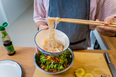 Téléchargez les photos : Chef à la cuisine préparant une salade de nouilles en verre épicé. - en image libre de droit