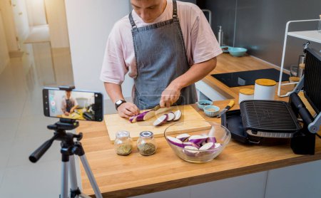 Foto de El chef está transmitiendo en vivo desde el taller cómo preparar una berenjena a la parrilla con ajo. - Imagen libre de derechos