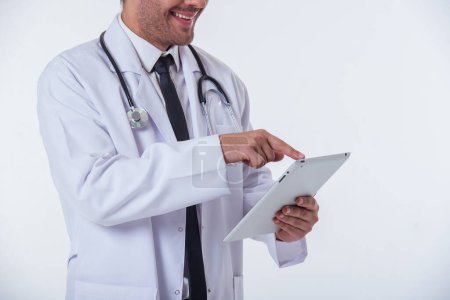 Cropped image of handsome doctor in white coat using a tablet and smiling, isolated on white background