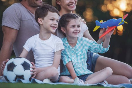 Téléchargez les photos : Cropped image de belle famille heureuse souriant tout en jouant avec l'avion jouet dans le parc - en image libre de droit