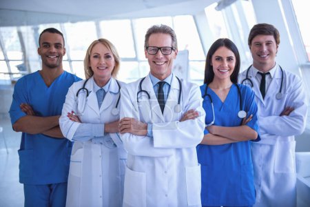 Photo for Successful team of medical doctors are looking at camera and smiling while standing in hospital - Royalty Free Image