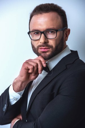 Foto de Retrato de caballero guapo en traje, pajarita y gafas, sobre fondo gris - Imagen libre de derechos