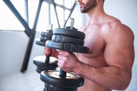 Foto de Imagen recortada de un hombre musculoso guapo con torso desnudo haciendo ejercicio con pesas - Imagen libre de derechos