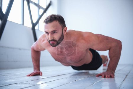 Photo for Handsome muscular man with bare torso is doing push-ups - Royalty Free Image