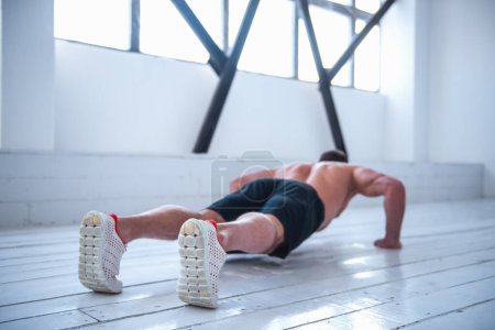 Foto de Vista posterior del hombre musculoso guapo con torso desnudo haciendo flexiones - Imagen libre de derechos