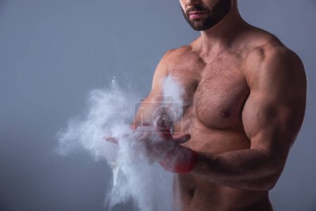 Foto de Imagen recortada de hombre musculoso guapo con torso desnudo usando talco corporal, sobre fondo gris - Imagen libre de derechos