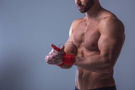 Foto de Imagen recortada de hombre musculoso guapo con torso desnudo usando talco corporal, sobre fondo gris - Imagen libre de derechos