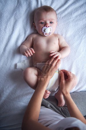 Foto de Mamá joven está cambiando su lindo pañal de bebé - Imagen libre de derechos