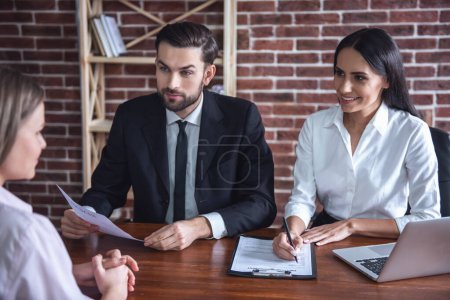 Foto de Hermosa pareja de empleadores en trajes están llevando a cabo una entrevista de trabajo mientras está sentado en la oficina - Imagen libre de derechos