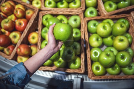 Téléchargez les photos : Au supermarché. Fruits frais attendant les clients, main de femme tenant une pomme - en image libre de droit