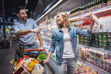 Téléchargez les photos : Beau couple parle et sourit tout en faisant du shopping au supermarché - en image libre de droit
