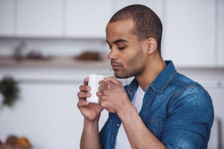 Téléchargez les photos : Beau homme boit du café dans la cuisine - en image libre de droit