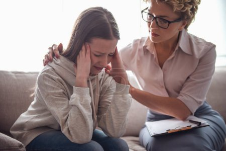 Photo for Teenage girl at the psychotherapist. Doctor is calming her patient while girl is crying - Royalty Free Image